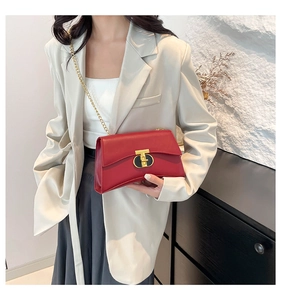 Détail du sac à bandoulière en cuir rouge avec fermoir en T doré et bandoulière chaîne