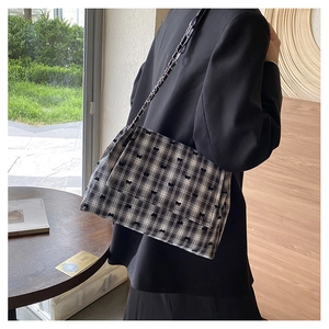 Détail du sac à carreaux avec imprimés nœuds et bandoulière chaîne sur un mannequin