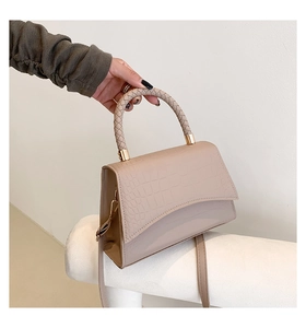 Macro detail of beige crocodile embossed leather bag with woven handle and gold hardware