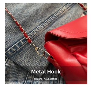 Détail du sac en cuir grainé rouge avec crochet métallique argenté et bandoulière chaîne