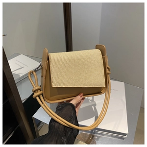 Detailansicht der braunen Leder-Nähte mit einer beige geflochtenen Strohklappe an der Tasche