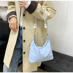 Detail of light blue crossbody bag with white marble beads and thin shoulder strap