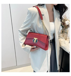 Détail du sac à bandoulière en cuir rouge avec chaîne métallique et fermoir sobre