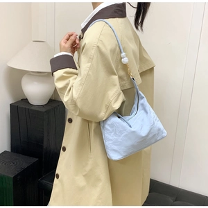 Detail view of light blue nylon hobo bag featuring decorative white pearl shoulder strap