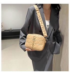 Détail du sac photo beige en cuir matelassé avec bandoulière tissée et gland