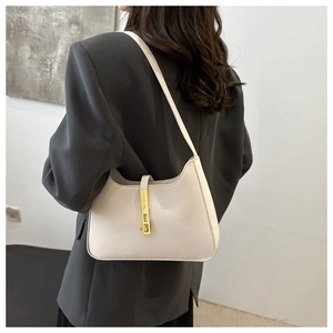 Detail of elegant cream hobo bag with gold piston lock shown on shoulder