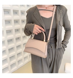 Detail of beige crocodile pattern handbag with braided handle and gold hardware