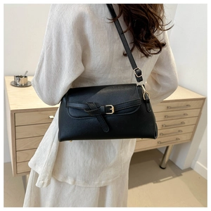 Detailed back view of a minimalist black leather crossbody bag worn by a model in a room