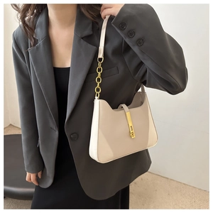Detail of beige leather shoulder bag featuring a gold clasp and metal chain strap