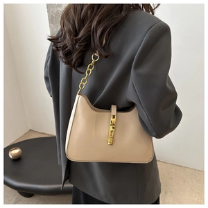 Détail du sac demi-lune beige avec bandoulière chaîne dorée et fermoir métallique
