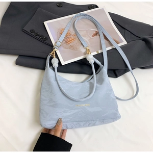 Detail of light blue textured shoulder bag with marble charm and Fashion & Bag logo