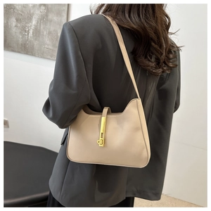 Detail of beige crescent hobo bag with gold metal buckle shown on a shoulder