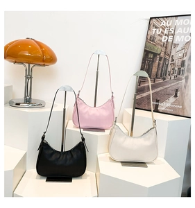 Three crescent hobo bags in black, pink and beige displayed on geometric stands