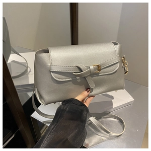 Detail of silver metallic handbag with knotted buckle and fine strap on white display
