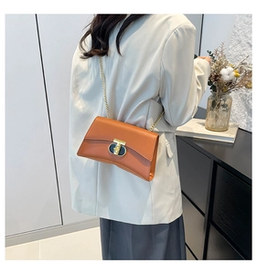 Détail d'un sac bandoulière en cuir marron avec fermoir en T doré et chaîne