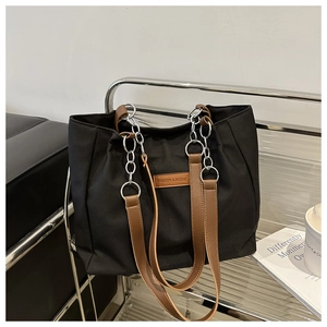 Close-up of black nylon tote bag with brown leather straps and silver metal chain link detail