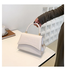 Detail of white crocodile-embossed handbag with woven handle and gold metal hardware