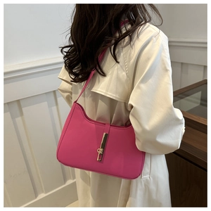 Close-up of bright pink crescent shoulder bag with golden piston clasp on leather