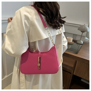 Sac hobo magenta chic avec fermoir doré porté sur un trench-coat élégant