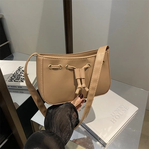 Beige faux leather underarm bag with gold eyelets and drawstring on mirror stand