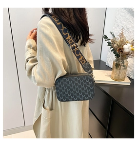 Side view of dark grey crossbody bag with M-pattern print and wide jacquard strap