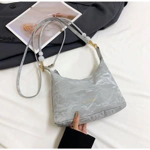 Detail of silver pleated crossbody bag with gold hardware and marble bead shoulder strap