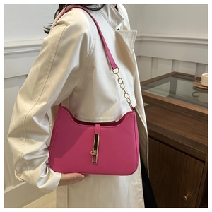 Gros plan sur un sac baguette rose vif avec fermoir doré et détail de chaîne sur manteau