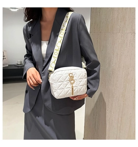 Détail d'un sac à bandoulière matelassé blanc avec logo S doré et sangle large