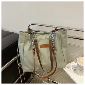 Close-up of mint green tote bag on modern chair with silver chain and leather logo detail