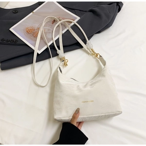 Detail of white nylon tote bag with gold logo text and round bead strap accents