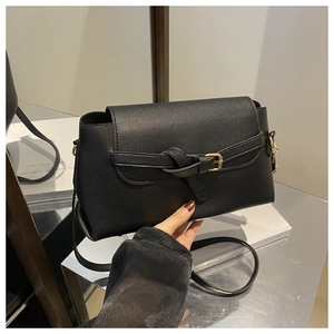 Detail of black leather crossbody bag with knot belt design and gold metal buckle