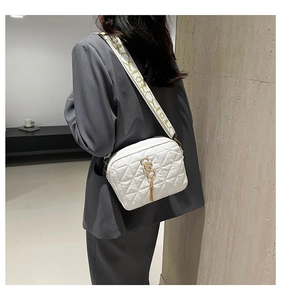 Détail d'un sac bandoulière matelassé blanc avec logo S doré et sangle tissée
