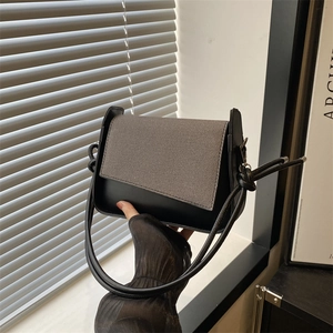 Minimalistische schwarze Ledertasche mit grauer Webklappe und geknotetem Schultergurt