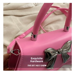 Gros plan sur un sac à main rose avec un détail décoratif de nœud en métal argenté brillant