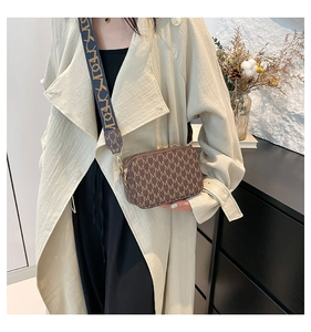 Close-up of brown crossbody bag with M-pattern and woven geometric shoulder strap