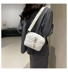 Gros plan d'un sac bandoulière matelassé blanc avec pompon doré et large sangle