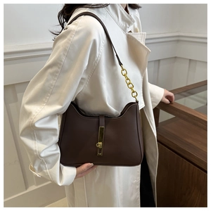 Detail of dark brown leather underarm bag with gold buckle and chunky chain metal strap