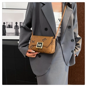 Detail view of brown leather shoulder bag with black letter print and gold M metal buckle