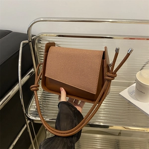 Schicke braune gewebte Umhängetasche mit Lederfinish auf einem eleganten Metallständer