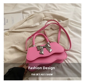 Détail du sac rose à nœud avec rabat ondulé et boucle en métal argenté sur tissu