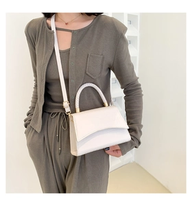 White crocodile pattern handbag with woven handle and gold hardware on model