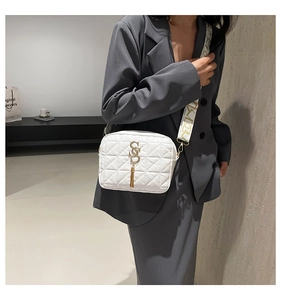 Détail d'un sac à bandoulière matelassé blanc avec accents dorés et large sangle
