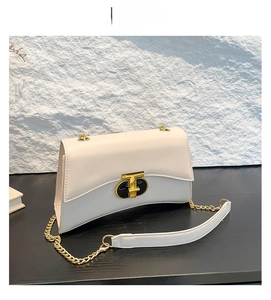 Détail d'un sac carré blanc avec un fermoir rotatif en métal doré et noir élégant