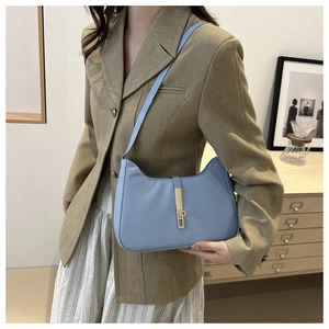 Detail view of light blue leather underarm bag featuring a sleek golden metal clasp buckle