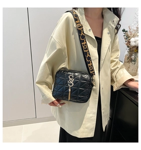 Détail du sac bandoulière noir matelassé avec boucle en S dorée et large sangle jacquard
