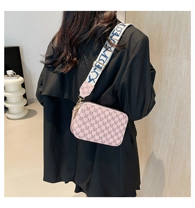 Detail shot of pink monogram crossbody bag with stylish wide blue-white textile strap