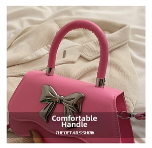 Gros plan détaillé du sac à main rose avec un grand nœud décoratif en métal argenté