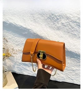 Détail de la texture en cuir marron et du fermoir doré de ce sac à bandoulière chaîne