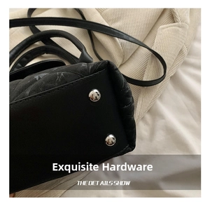 Detailed macro shot of silver protective studs on the base of a black quilted bucket bag