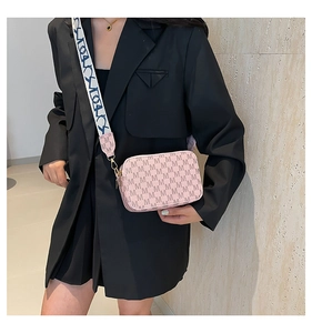 Detailed shot of pink leather crossbody bag with double zippers and wide jacquard strap